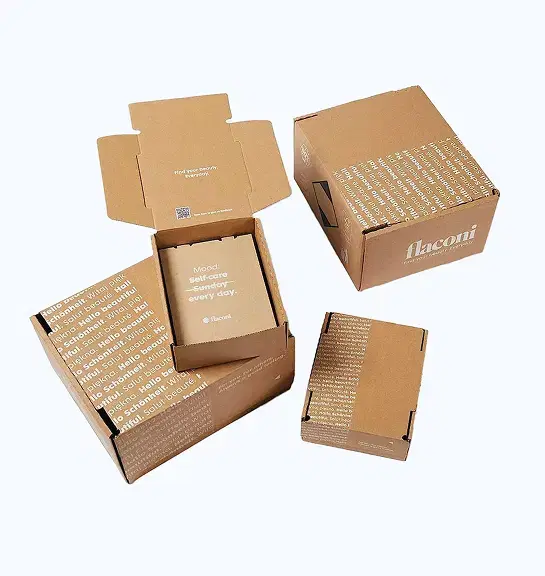 Cluster of light brown corrugated cardboard boxes with multilingual branding including 'Hello beautiful', 'flaconi' logo, and 'Find your beauty. Everyday' messaging