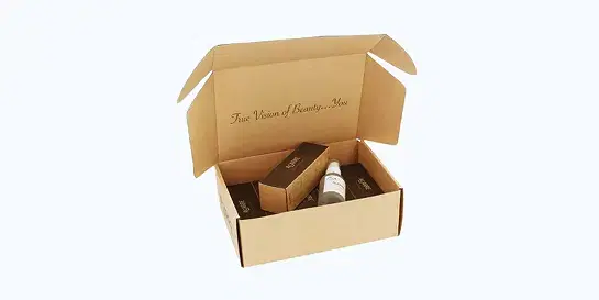 Open light brown corrugated box containing dark product boxes and a white bottle, with elegant cursive script 'True Vision of Beauty... You' on inner flap